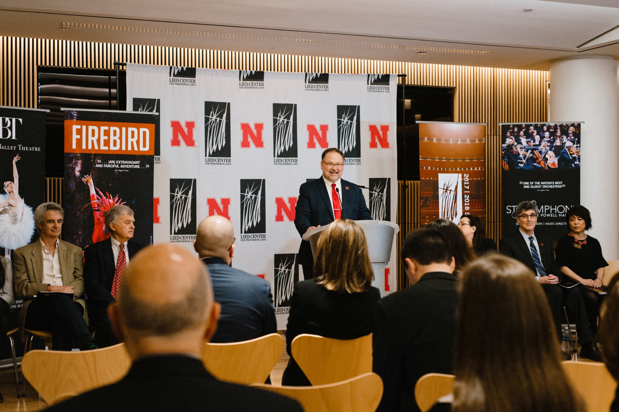 Image of the press conference announcing the Firebird performance showing Bill Stephan at the podium in front of the Lied Center and University of Nebraska backdrop