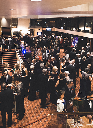 Image of the Lied Center Orchestra Lobby filled with dozens of partygoers in fancy dress enjoying cocktails before the Friends of Lied gala