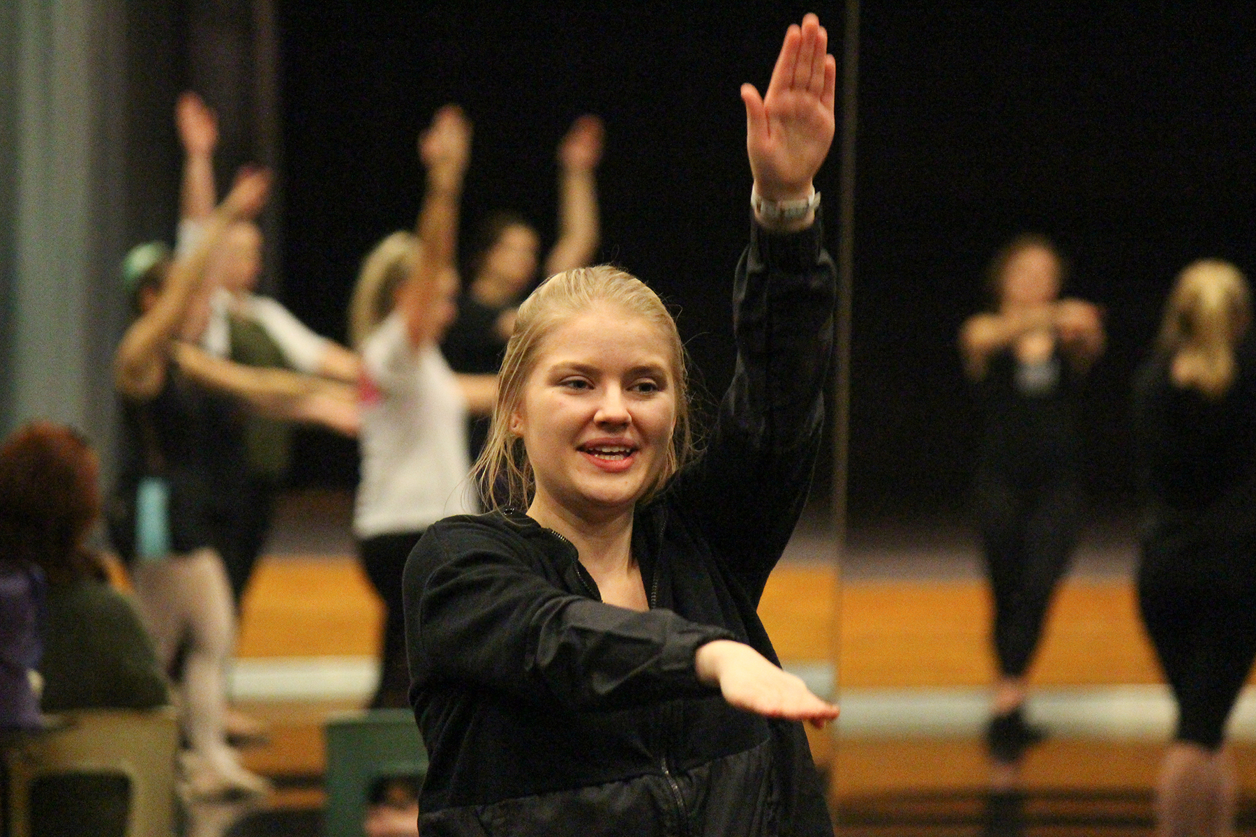 Image of a UNL student with her right arm raised and left arm pointing forward during the Trinity Irish Dance master class