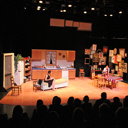 Image of a play hosted in the Lied Center Johnny Carson Theater featuring a set that looks like a living room and kitchen.
