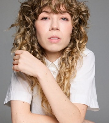 headshot of a woman with wavy hair in white tee shirt