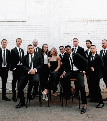 a group of humans dressed in black suits and dresses pose together