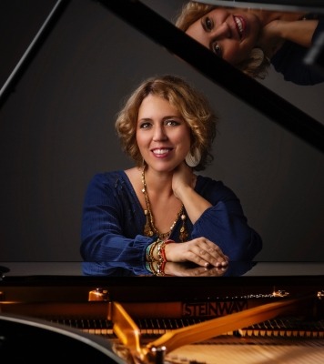 A woman sitting at a piano and smiling at the camera