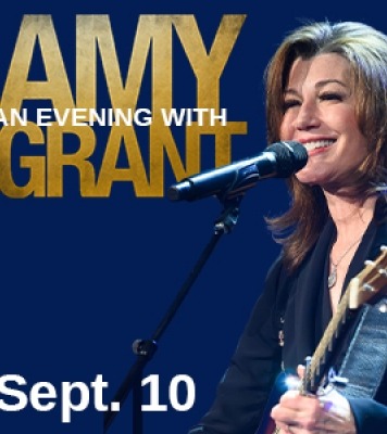 A woman with brown hair and a guitar singing into a microphone with "An Evening with Amy Grant" in gold and white letters