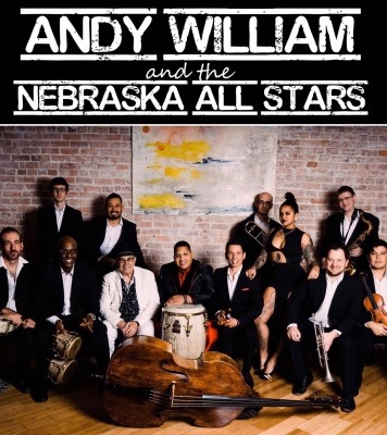 a group on classy-dressed musicians posed together against a brick wall