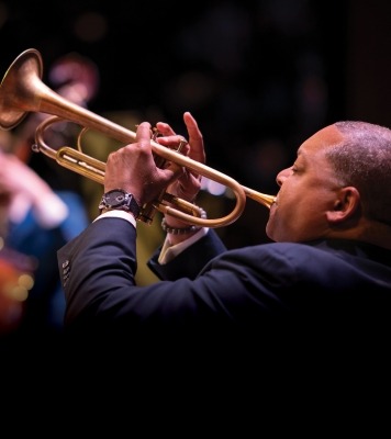 a man in a suit with a short haircut plays the trumpet