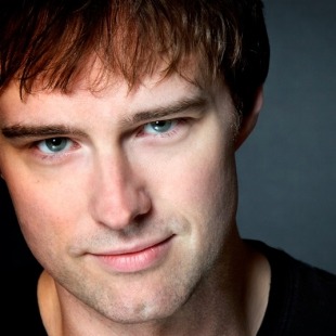 a very close-up shot of a man with brown hair smirking