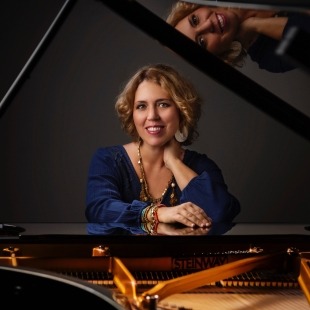 A woman sitting at a piano and smiling at the camera