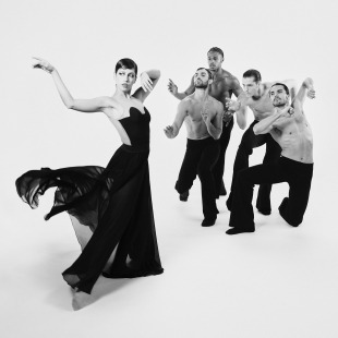 a woman dancer featured in front of a gaggle of shirtless male dancers