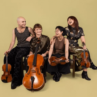 four musicians pose together in front of a tan background