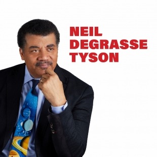 Dark skinned man with a black suit jacket and colorful tie with his face resting on his hand.