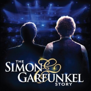 Two men facing away from the camera on a stage with blue lights shining onto the stage. Text at the bottom of the stage reads "The Simon & Garfunkel Story"