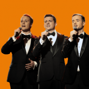 Three men in tuxedos stand side by side facing the camera and singing into handheld microphones 
