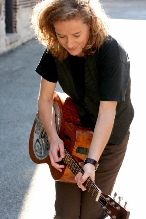 Susan Werner outside playing her guitar