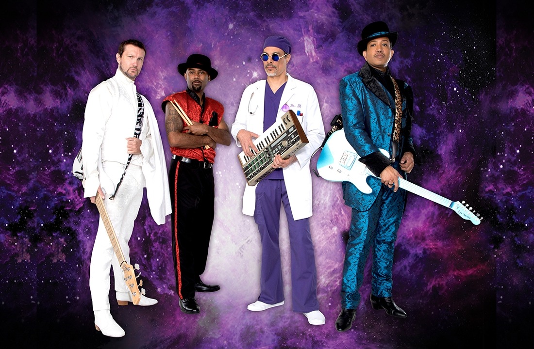 Image of the backing band for Purple Rain dressed in their various costumes standing in front of a purple background.