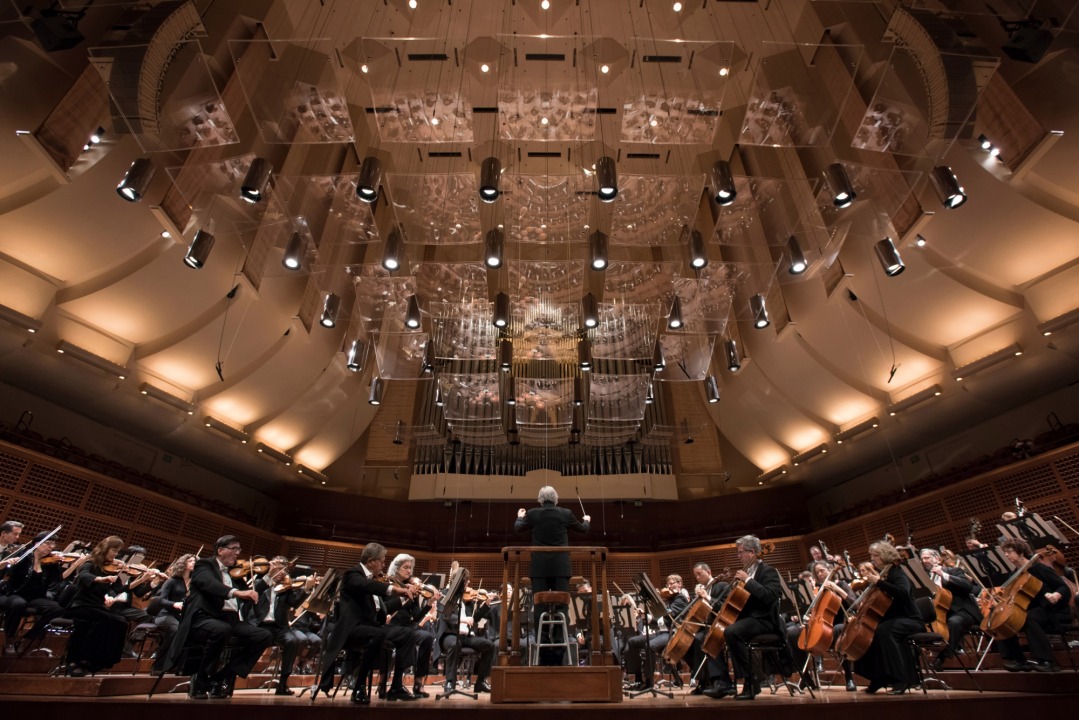 Image of Michael Tilson Thomas conducting the symphony on stage