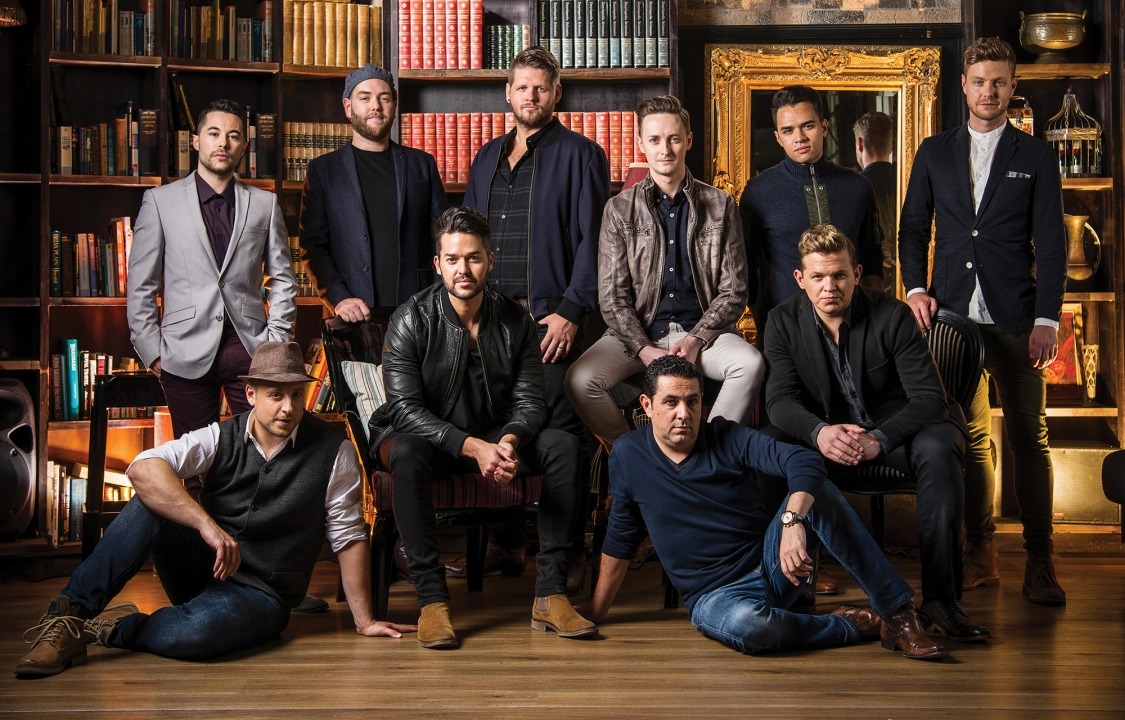 Ten men posed in front of a large bookcase looking at the camera
