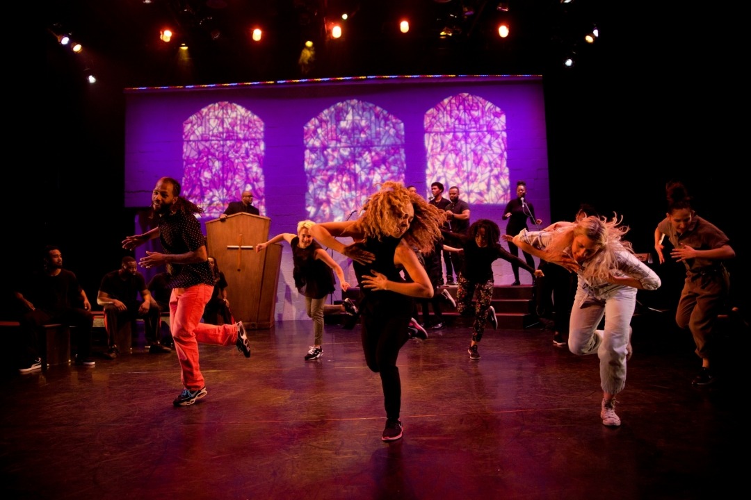 Dance group dancing with screens in the background portraying stained glass images