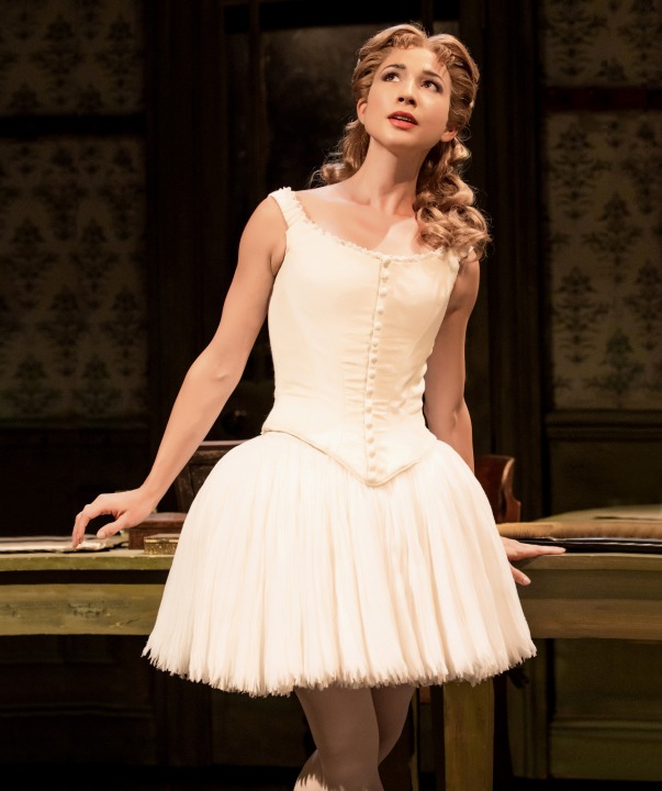Woman in white ballerina costume in front of a brown background.