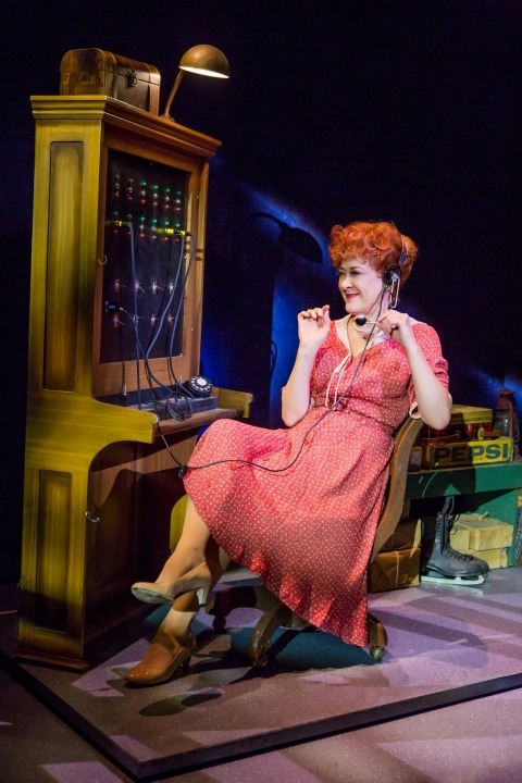 Woman in a red dress with a headset on sitting at a switchboard