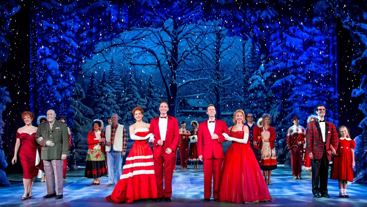 Men and women standing in couples dressed in red in front of a snowy forest background