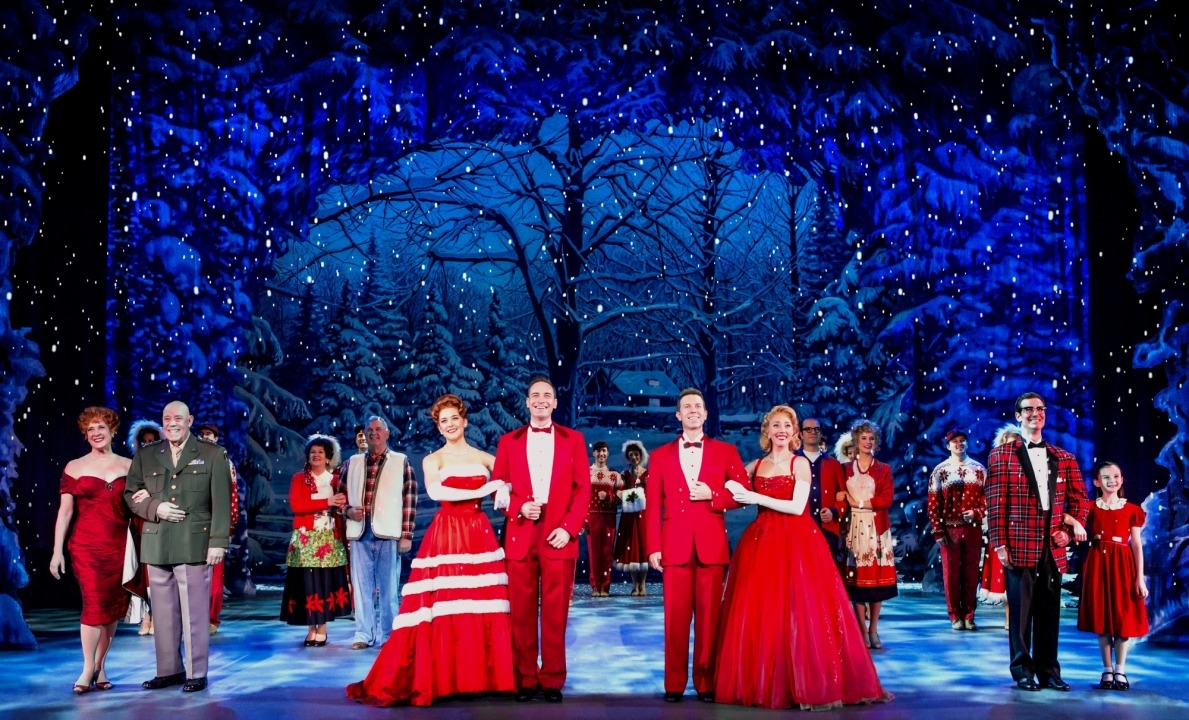 Men and women standing in couples dressed in red in front of a snowy forest background