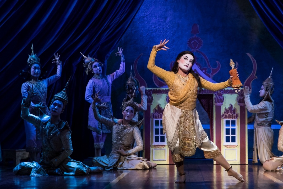 man in costume dancing with four other people in costume behind him and a blue background