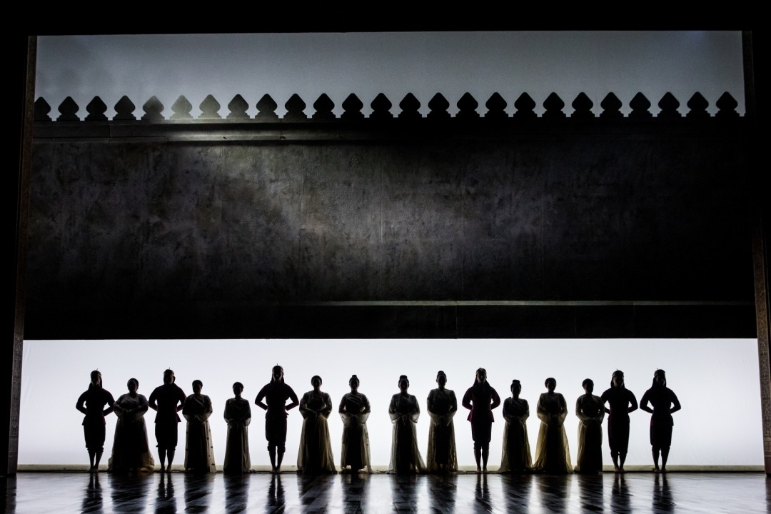 Sixteen shadowy figures standing in a line with a white and black background