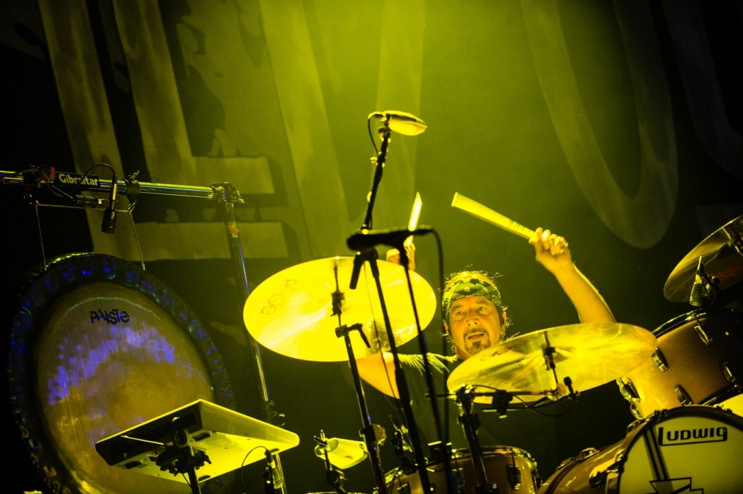 A yellow tinted photo of a man playing the drums.