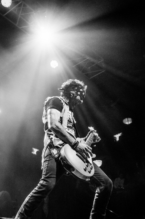 A black and white photo of a man with his mouth open playing the electric guitar