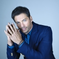 Harry Connick Jr wearing a blue blazer against a blue background.