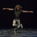 Man wearing dark clothes dancing with a black background