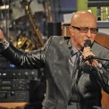 Paul Shaffer wearing a suit and singing into a microphone