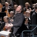 Close up of a man conducting the orchestra with strings section in the background