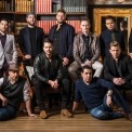 Ten men posed in front of a large bookcase looking at the camera