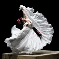 Woman in a white dress dancing on a platform with the skirt of her dress fanned out