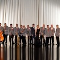 An image of the Glenn Miller Orchestra standing on stage holding their instruments but not playing them