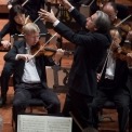 Close up and side angle of Michael Tilson Thomas conducting the symphony