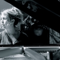 Image of Gabriela Monteri in black and white, seated at a piano glancing pensively to her right.