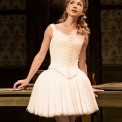 Woman in white ballerina costume in front of a brown background.