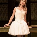 Woman in white ballerina costume in front of a brown background.