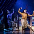 man in costume dancing with four other people in costume behind him and a blue background