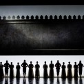 Sixteen shadowy figures standing in a line with a white and black background