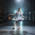  Woman in a blue dress and red shoes in a room with a blue light behind her