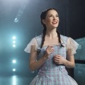  Woman in a blue dress and red shoes in a room with a blue light behind her