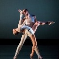 A man and woman wearing white dancing in front of a black background