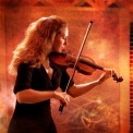 A woman in a black dress playing a violin in front of an orange background.