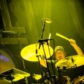 A yellow tinted photo of a man playing the drums.