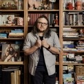 Jeff Tweedy standing in front of a bookcase.