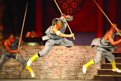 Man in grey costume performing Martial Arts with a Rattan stick